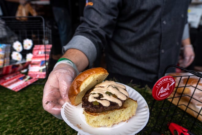 Executive Chef Tommy D'Ambrosio of Aioli Gourmet Burgers poses with a burger for patrons to sample during the 14th annual Devour Culinary Classic at the Desert Botanical Garden in Phoenix on Feb. 25, 2023.