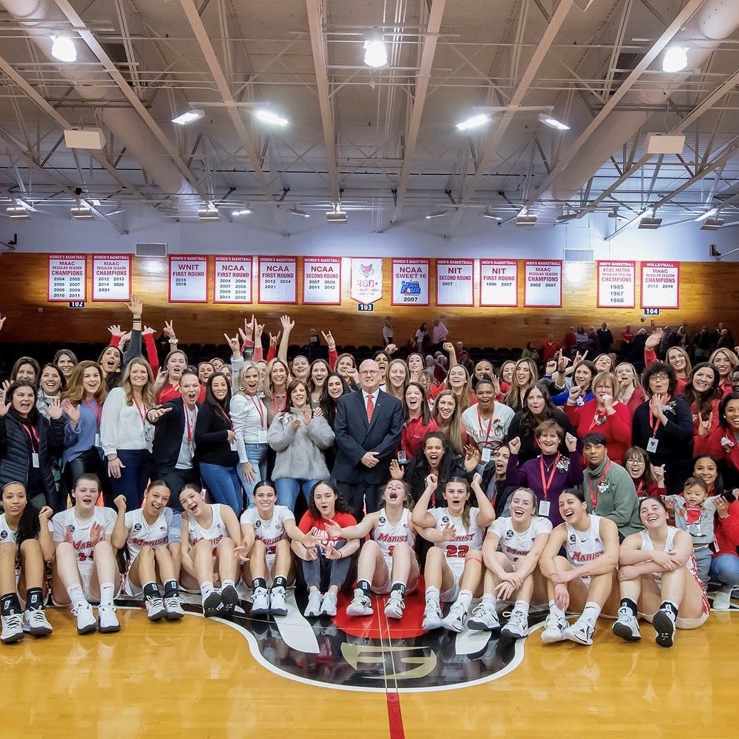 Marist College women's basketball coach Brian Giorgis, center, poses while surrounded by current and former players who returned to the school Saturday for his final home game before retirement.