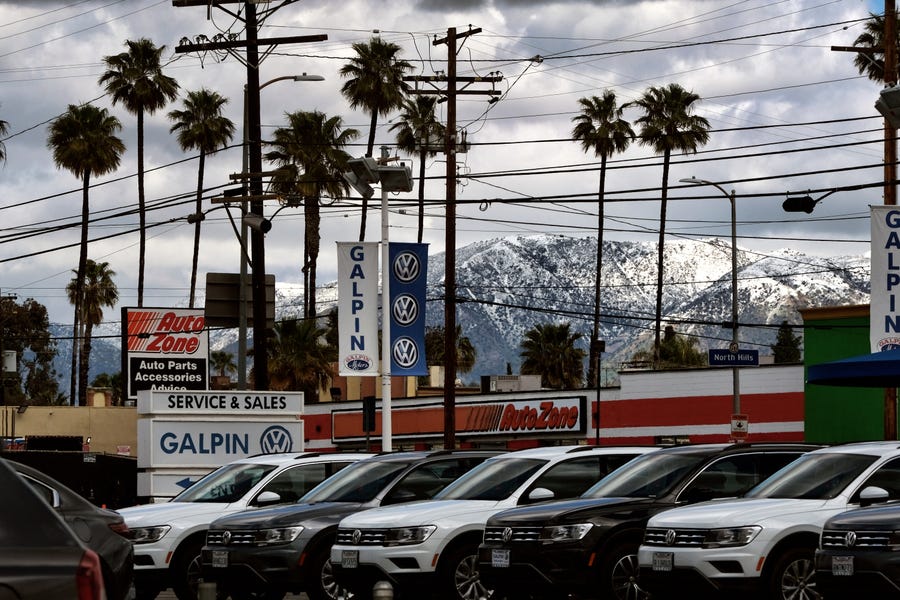 Snow covers the San Gabriel mountain range behind a used car lot in the Mission Hills section of the San Fernando Valley on Sunday. A powerful winter storm that swept the West Coast with flooding and frigid temperatures has shifted to southern California, swelling rivers to dangerous levels and dropping snow in even low-lying areas around Los Angeles.