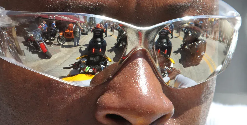 Bikers are reflected in the glass of a biker riding west on Main Street in Daytona Beach as Bike Week hits its final days in 2013.