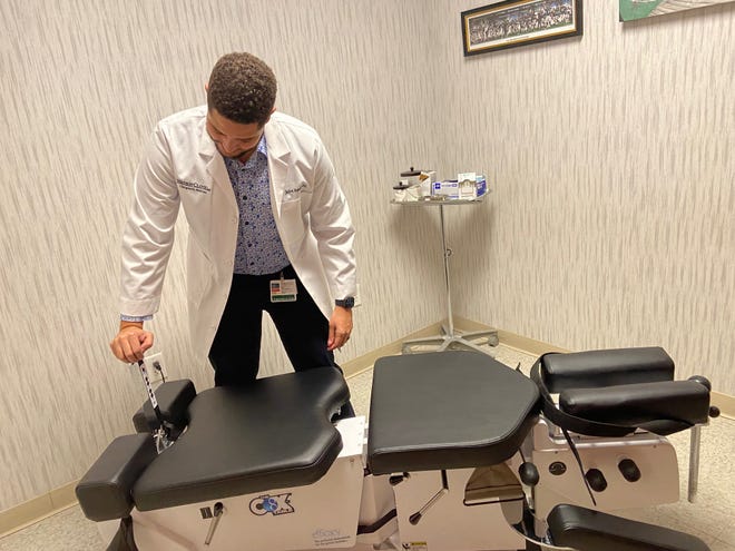 Jalen Banks, a chiropractor at Watson Clinic, demonstrates a Cox Flexion Distraction table he uses at Watson Clinic Center for Specialized Rehabilitation.