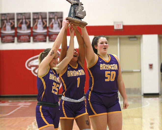 Bronson seniors Addison Harris, Haylie Wilson and Helena Eley celebrate with the district title trophy on Friday afternoon in Constantine.