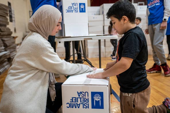 Volunteers for Islamic Relief USA gather at Al-Ghazaly High School in Wayne, NJ on Saturday, March 4, 2023 to pack boxes of food to combat food insecurity. Yesmeen, 18 and Said, 8 tape up boxes to be filled with food.