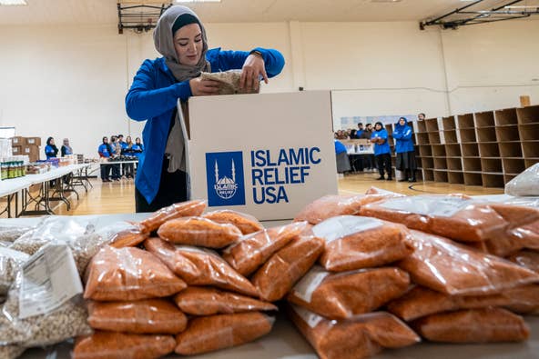 Dima AKach, the lead volunteer engagement specialist for Islamic Relief USA, demonstrates how to package a box of food at Al-Ghazaly High School in Wayne, NJ on Saturday, March 4, 2023. The boxes of food will be distributed to combat food insecurity.