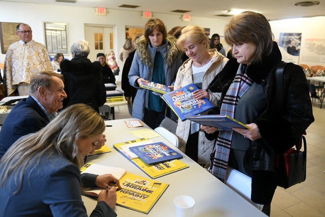 Dari kiri, Penulis Michael Sampson dan Olena Kharchenko menandatangani salinan buku mereka "Kisah Ukraina: Lagu Kemuliaan dan Kebebasan" untuk, dari kanan, Nadia Rak dari West Bloomfield dan Svetlana Marva dari Hamtramck di Gereja Katolik Ukraina Dikandung Tanpa Noda di Hamtramck, Mich. pada 5 Maret 2023.
