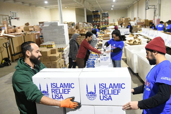 Ayham Al-Shebli, left, 30, of Dearborn and Talal Alothman, 32, of Ann Arbor arrange boxes of food on a pallet as volunteers pack up boxes of food for the Islamic Relief USA.