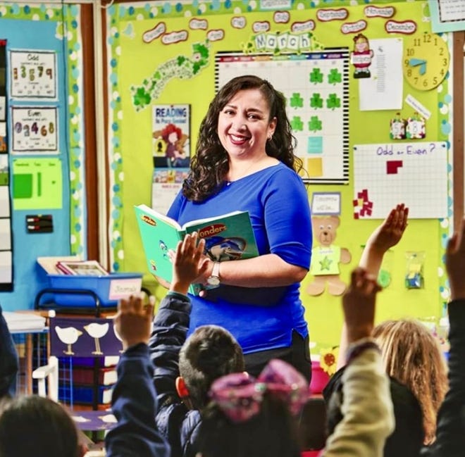 Sonia Aguila, the 2023 National Bilingual Teacher of the Year, poses in her classroom with a textbook.