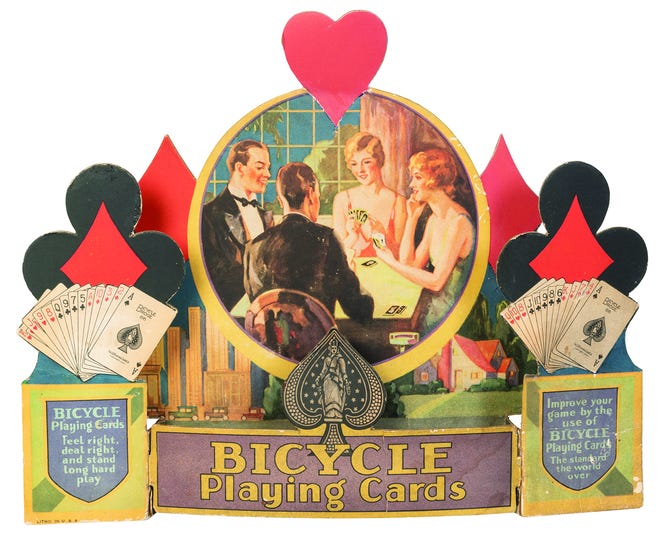 When advertisements include pictures of people, their clothing and hairstyles can help date the item. This store display for Bicycle Playing Cards is from about 1930.