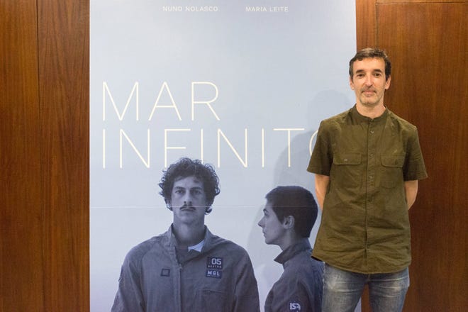 Regizorul portughez Carlos Amaral stă lângă afișul primului său lungmetraj "mare infinită" (Infinite Sea), care vine pe Amazon Prime Video și Vudu pe 24 martie.