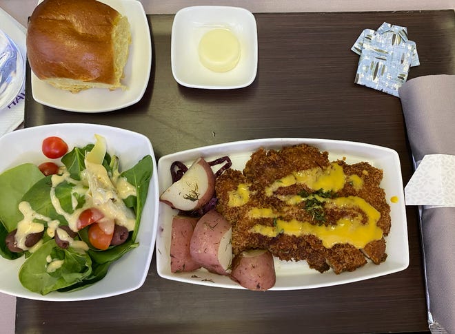 O schnitzel de frango é servido com repolho roxo refogado e batatas.  Uma garoa de mostarda lilikoi adiciona um pouco de ácido ao prato saboroso.