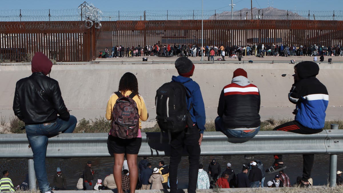 FILE - Migrants watch others stand next to the border wall in Ciudad Juarez, Mexico, Dec. 21, 2022, on the other side of the border from El Paso, Texas. A new poll by The Associated Press-NORC Center for Public Affairs Research shows some support for changing the number of immigrants and asylum-seekers allowed into the country. About 4 in 10 U.S. adults say the level of immigration and asylum-seekers should be lowered, while about 2 in 10 say they   should be higher, according to the poll. About a third want the numbers to remain the same. (AP Photo/Christian Chavez, File) ORG XMIT: WX211