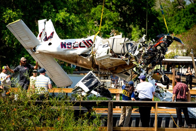 Investigators view the wreckage of a Piper PA-28 Cherokee fixed-wing aircraft after it is hoisted out of Lake Hartridge in Winter Haven on Thursday. Four people died when the Cherokee and a Piper J-3 Cub seaplane collided over the lake Tuesday.