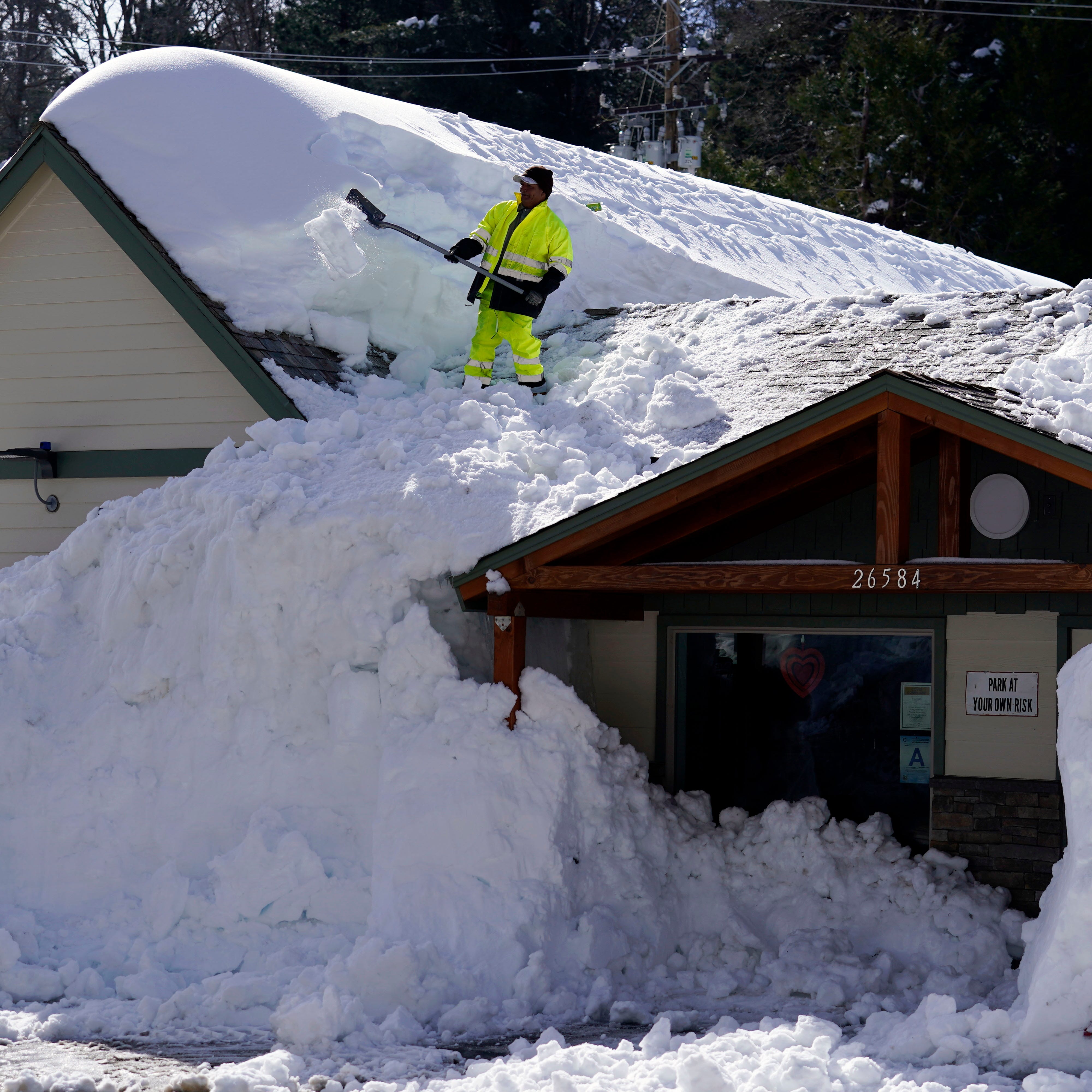 March 8, 2023: A worker clears snow off the roof of Skyforest Elks Lodge after a series of storms, in Rimforest, Calif.