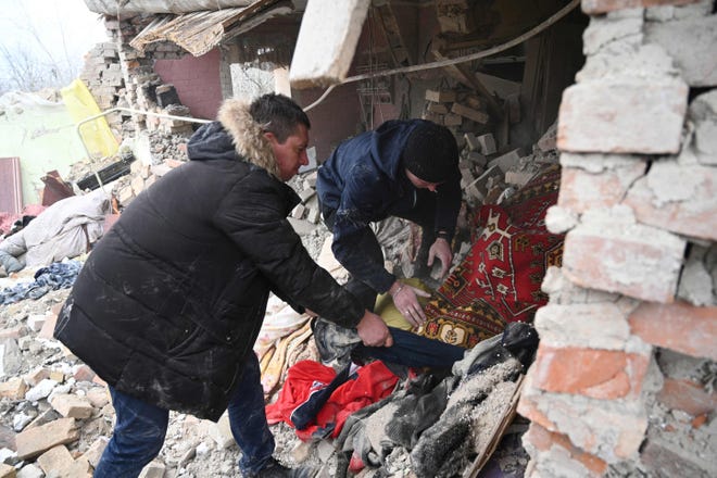 La gente perquisisce le rovine di una casa a seguito di un attacco russo nel villaggio di Velika Vilshanitsya vicino a Lviv il 9 marzo 2023.