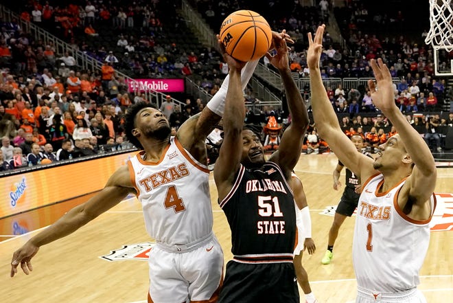 Oklahoma State's John-Michael Wright shoots under pressure from Texas' Tyrese Hunter, left, and Dylan Disu during the first half of UT's 61-47 win Thursday in the Big 12 Tournament. The Longhorns advanced to Friday's semifinals.
