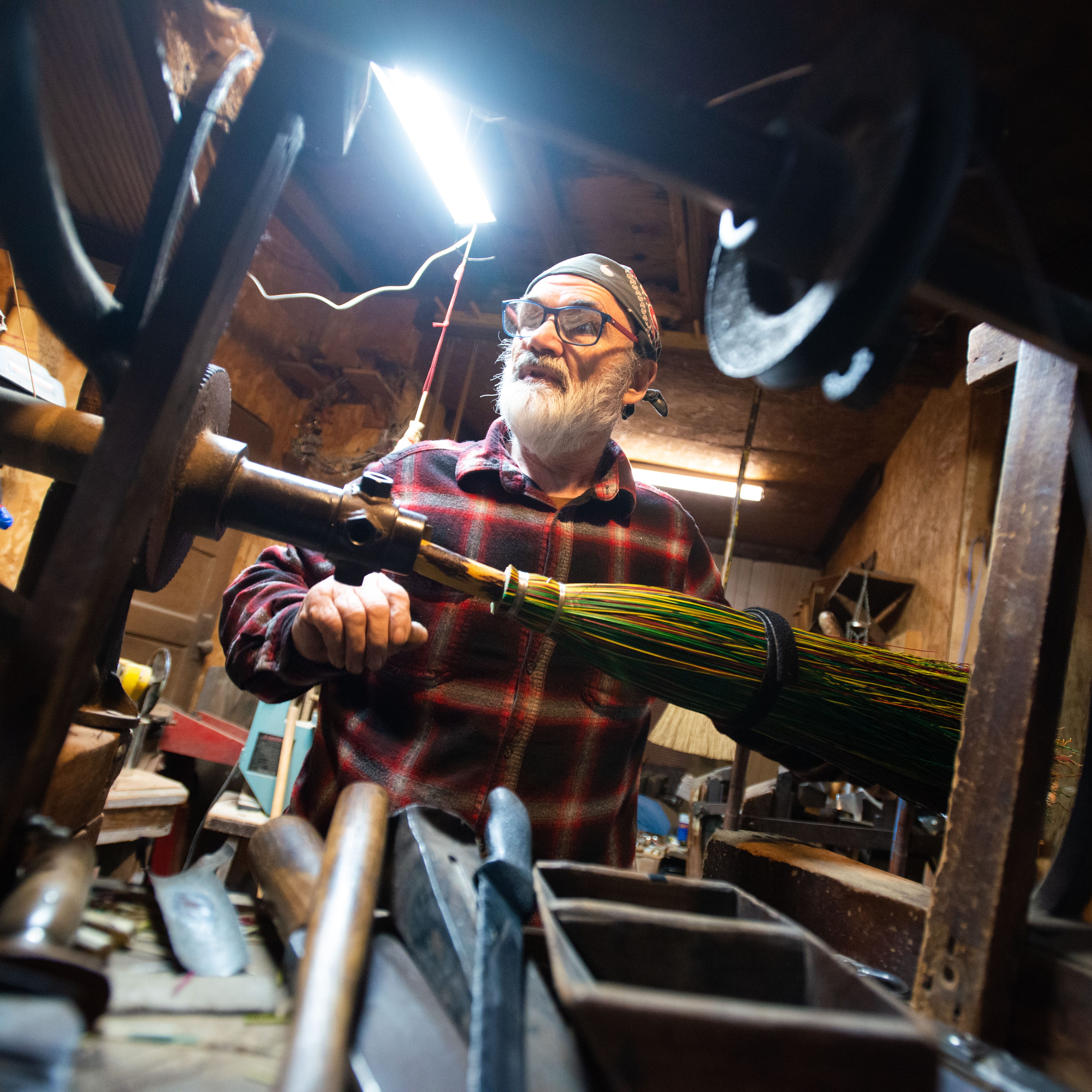 Broom-maker Jack Martin looks for a special tool to finish off the broomcorn inside Hockaday Brooms in Selmer, Tenn. on Wednesday, Mar. 8, 2023.