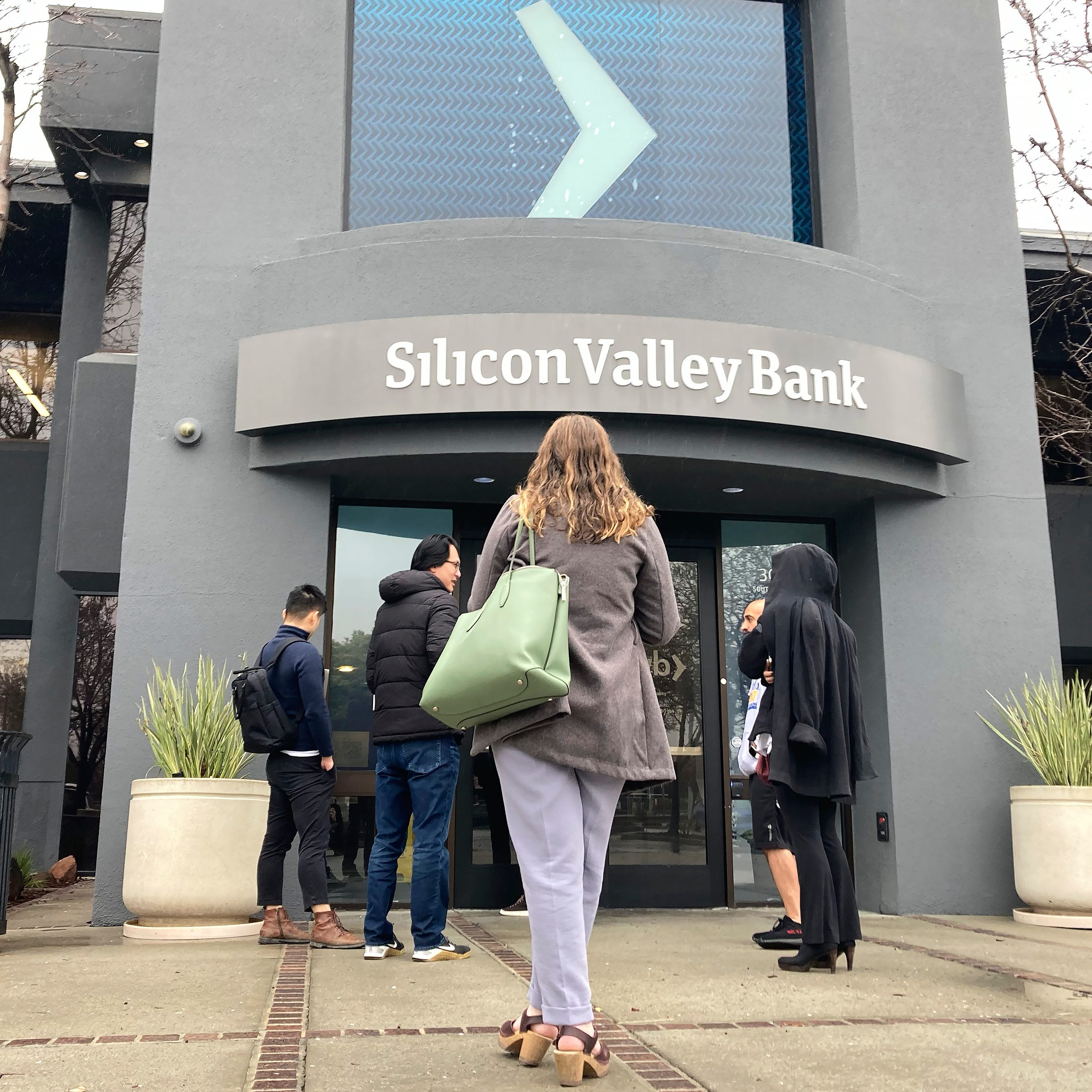 People stand outside of an entrance to Silicon Valley Bank in Santa Clara, Calif., Friday, March 10, 2023. The Federal Deposit Insurance Corporation seized the assets of the bank on Friday, marking the largest bank failure since Washington Mutual during the height of the 2008 financial crisis. (AP Photo/Jeff Chiu)