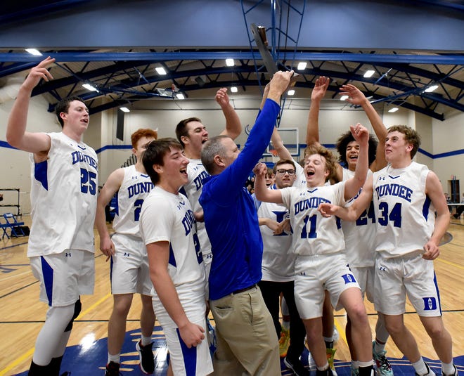 Gabe Daniel, Drew Bolster, Ryan Zanger, Ethan Layton, Braiden Whitaker and Adam Spare (from the left) celebrate with their teammates as Dundee head coach Jay Haselschwerdt raises the Division 2 district final trophy after beating Ida 53-51 Friday.