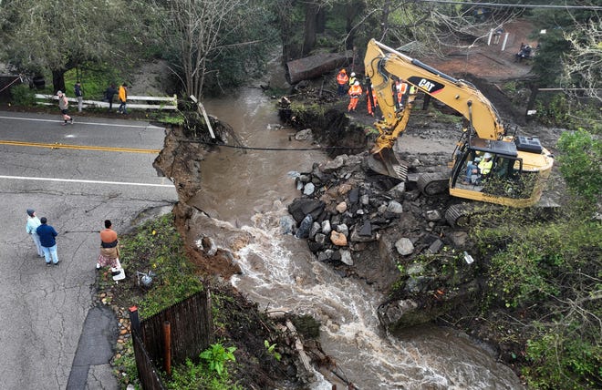 In an aerial view, workers make emergency repairs to a road that was washed out heavy rains on March 10, 2023 in Soquel, California. An atmospheric river event brought high winds and heavy rains to Northern California that caused localized flooding and toppled trees. A second atmospheric event will hit Northern California by Monday or Tuesday.