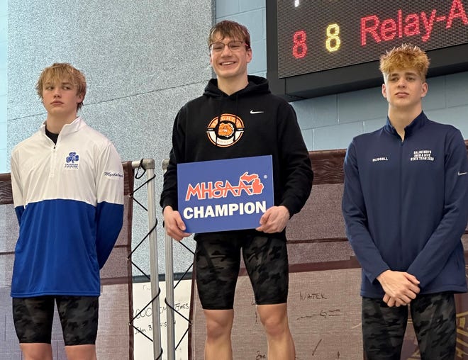 Brighton junior Luke Newcomb (center) won the state Division 1 championship in the 100-yard breaststroke Saturday, March 11, 2023 at Calvin University.