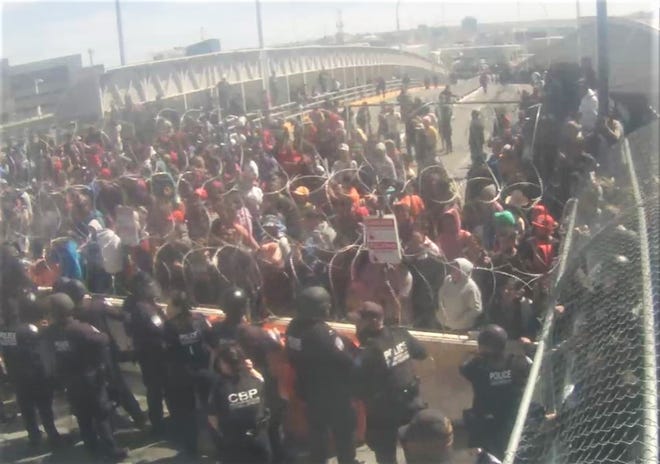 U.S. Customs and Border Protection officers in riot gear block migrants demanding entry on the Paso Del Norte Bridge at the border in Downtown El Paso and Juarez, Mexico, on Sunday, March 12, 2023.