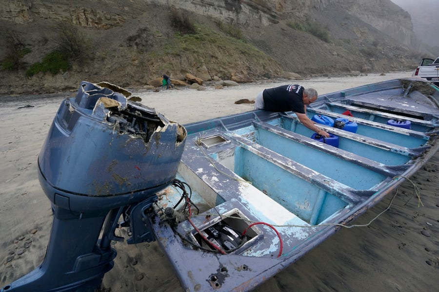 Boat salvager Robert Butler picks up a canister in one of one of two boats sitting on Blacks Beach on March 12, 2023, in San Diego.