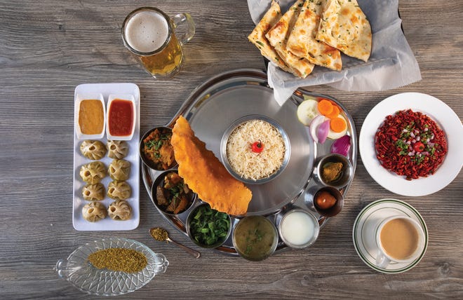 A spread from Jhapali Kitchen & Bar, from left: momos, Kingfisher beer, garlic naan, chatpata, chai and Nepalese goat thali