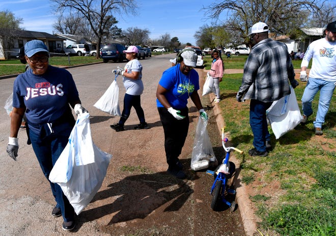 A mix of volunteers pick up litter along Congress Avenue in the Holiday Hills neighborhood Saturday. Over a dozen people participated in the neighborhood cleanup organized by From Boys to Gentlemen.
