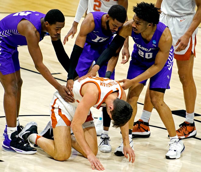 Abilene Christian players Mahki Morris, Reggie Miller and Coryon Mason check on Texas forward Brock Cunningham during the second half of their 2021 NCAA Tournament game. The Longhorns, who had just won the Big 12 Tournament the week before, were shocked by the Wildcats in the first round 53-52.
