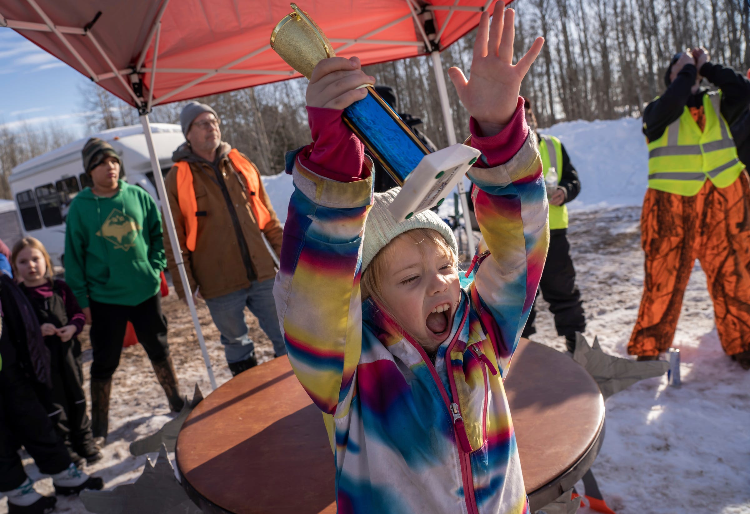 Addy Koponen, of Gwinn, cheers on others while holding her trophy at the end of the fourth annual K.I. Sawyer Cardboard Sled Races on Feb. 11, 2023 in Michigan's Upper Peninsula.