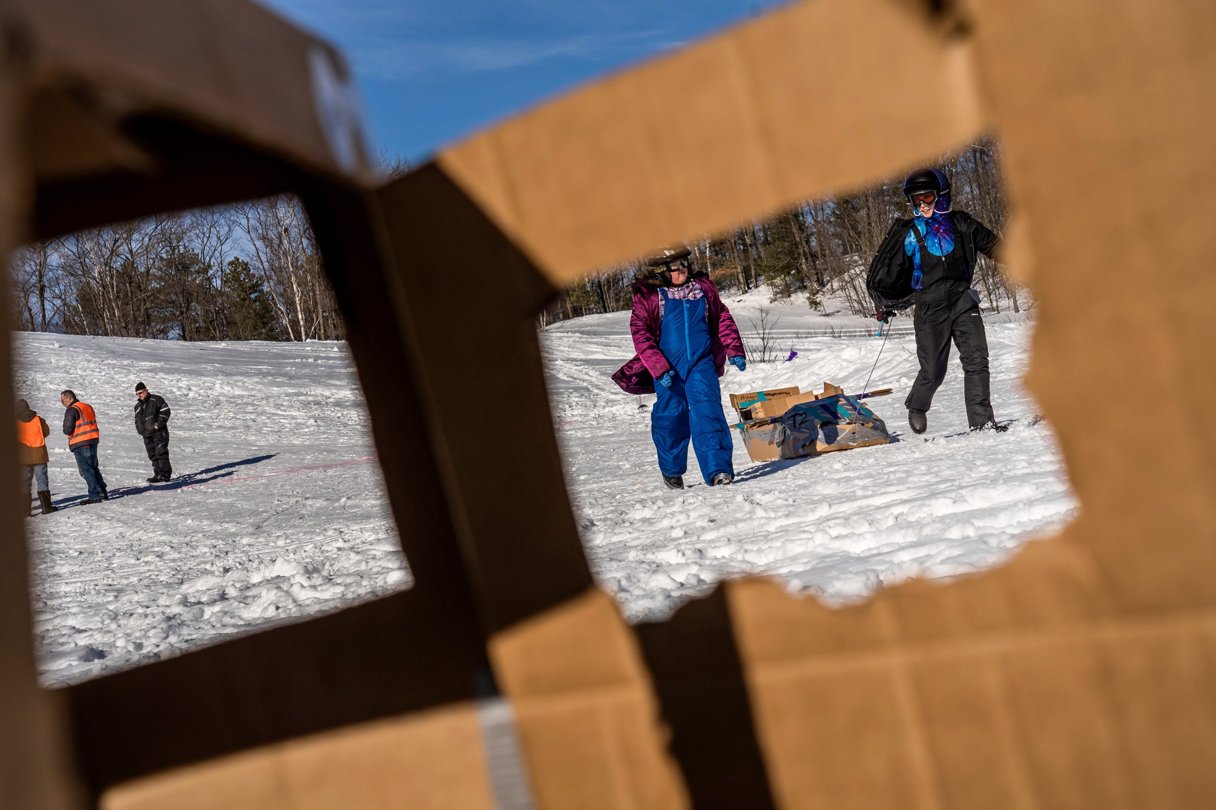 Bella Taylor, center, and her teammate Ashlyn Olvera, right, both of Gwinn, haul their cardboard sled away after competing in the K.I. Sawyer Community Cardboard Sled Races on Feb. 11, 2023.