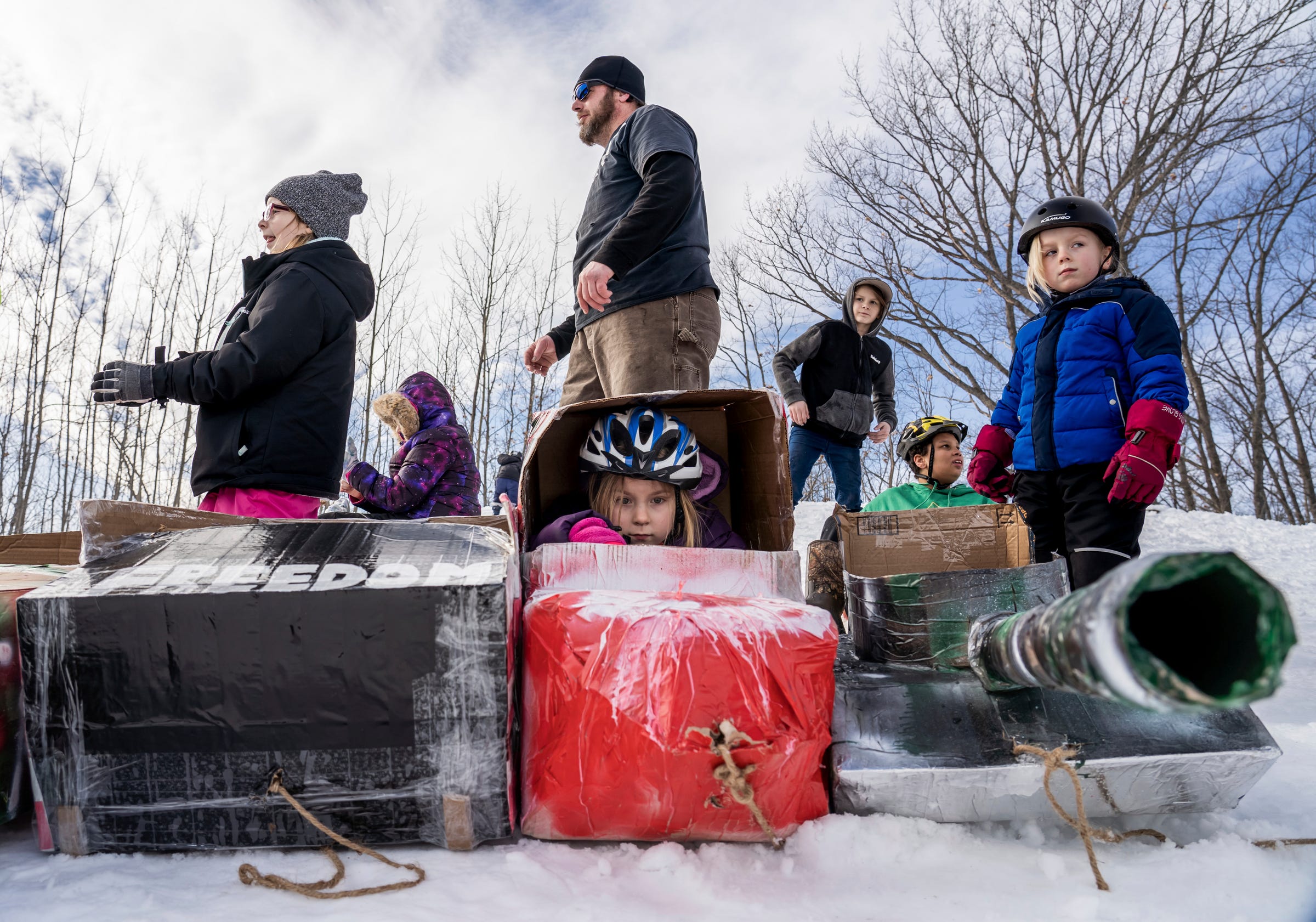 Isa Campbell, center, of Gwinn, sits in her cardboard sled as her father, Ambrose Campbell, of Gwinn, sister Aryanna Campbell, left, and brother Ambrose Brody Campbell Jr., right, wait for the start of the K.I. Sawyer Cardboard Sled Races on Feb. 11, 2023.