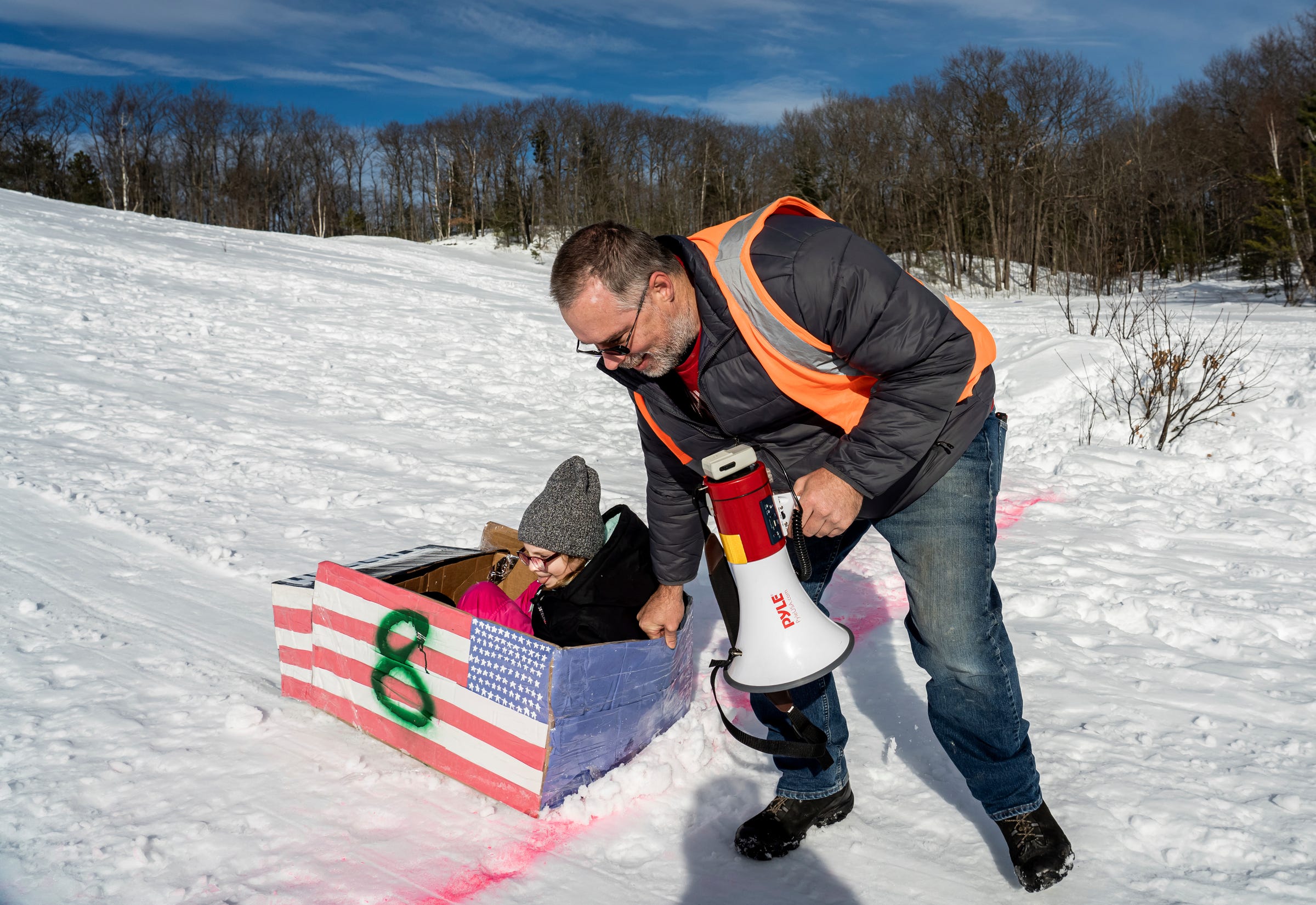 Ryan Lipinski helps pull Aryanna Campbell, of Gwinn, across the finish line after her sled got stuck midway down the hill during the K.I. Sawyer Cardboard Sled Races on Feb. 11, 2023.