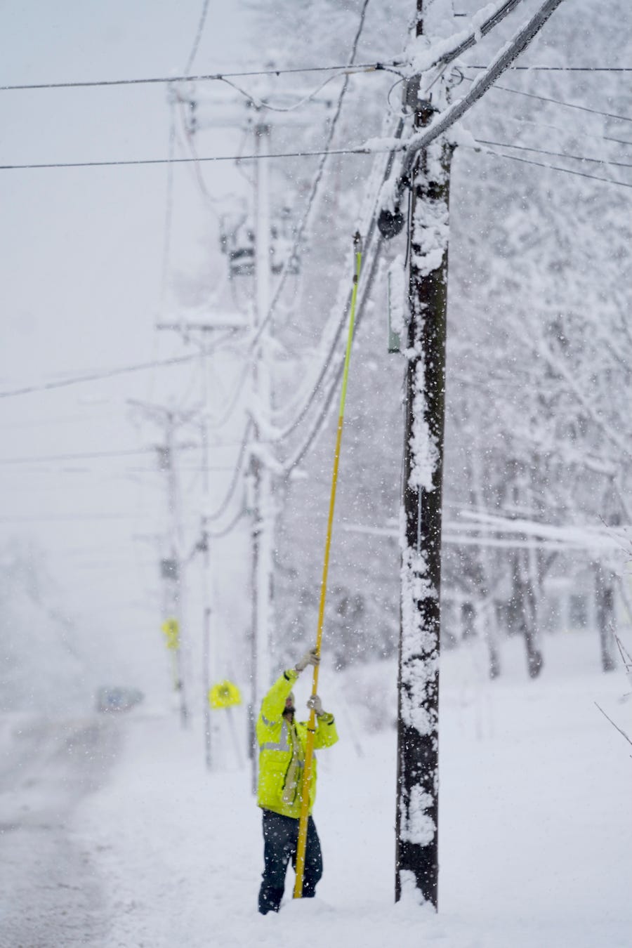 A contractor for Eversource uses a fiberglass pole to replace a fuse that broke, Tuesday, March 14, 2023, in Pittsfield, Mass. The New England states and parts of New York are bracing for a winter storm due to last into Wednesday. (Ben Garver/The Berkshire Eagle via AP)