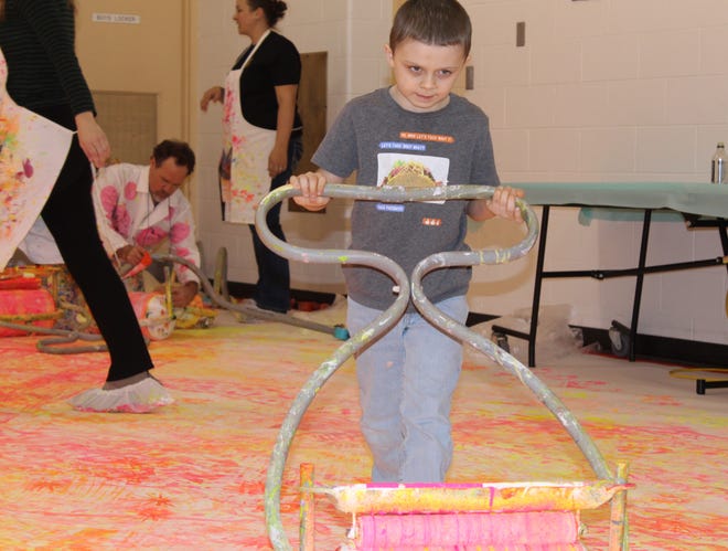 Cooper, a Monroe County Intermediate School District student, uses an art roller to make shapes of stars and swirls on a giant canvas. The artwork will commemorate the MCISD Education Center’s 50th anniversary.