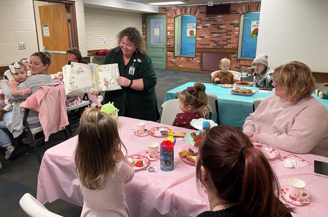 Janice Sycks, youth services coordinator for the Coshocton Public Library, reads "Tea Party Rules" by Ame Dyckman with illustrations by K.G. Campbell for a tea party at the program attended by 16 children and their guardians. The event featured snacks, drinks, bingo, an egg race and a hat making craft.