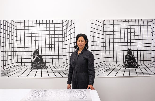 Artist Gina Osterloh with photos from her “Holding Zero” (background) and “Drawing for the Camera” (foreground) series
