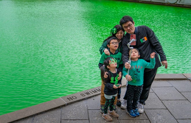 The Mita family poses for a selfie Thursday, March 16, 2023, at the canal in Indianapolis after it had been dyed green for St. Patrick’s Day.