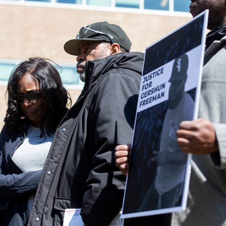 RowVaughn Wells and Rodney Wells, the parents of Tyre Nichols, listen to a speaker while standing next to Gilbert Barnes Carter III, a Memphis activist, holding a sign with Gershun Freeman's picture and the message 