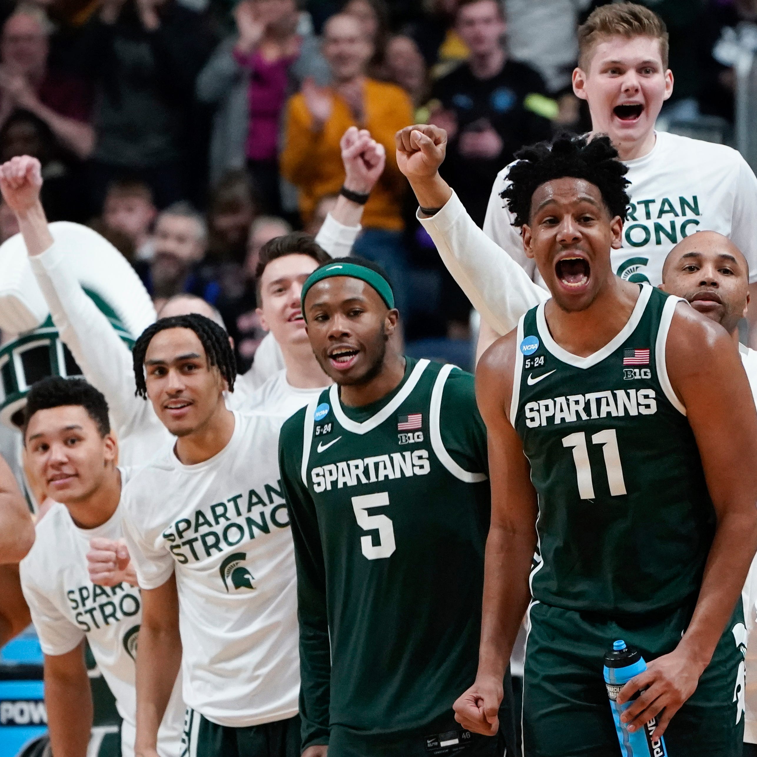 Michigan State players including Tre Holloman (5) and A.J. Hoggard (11) celebrate on the bench during their second-round win over Marquette in the NCAA men's basketball tournament.