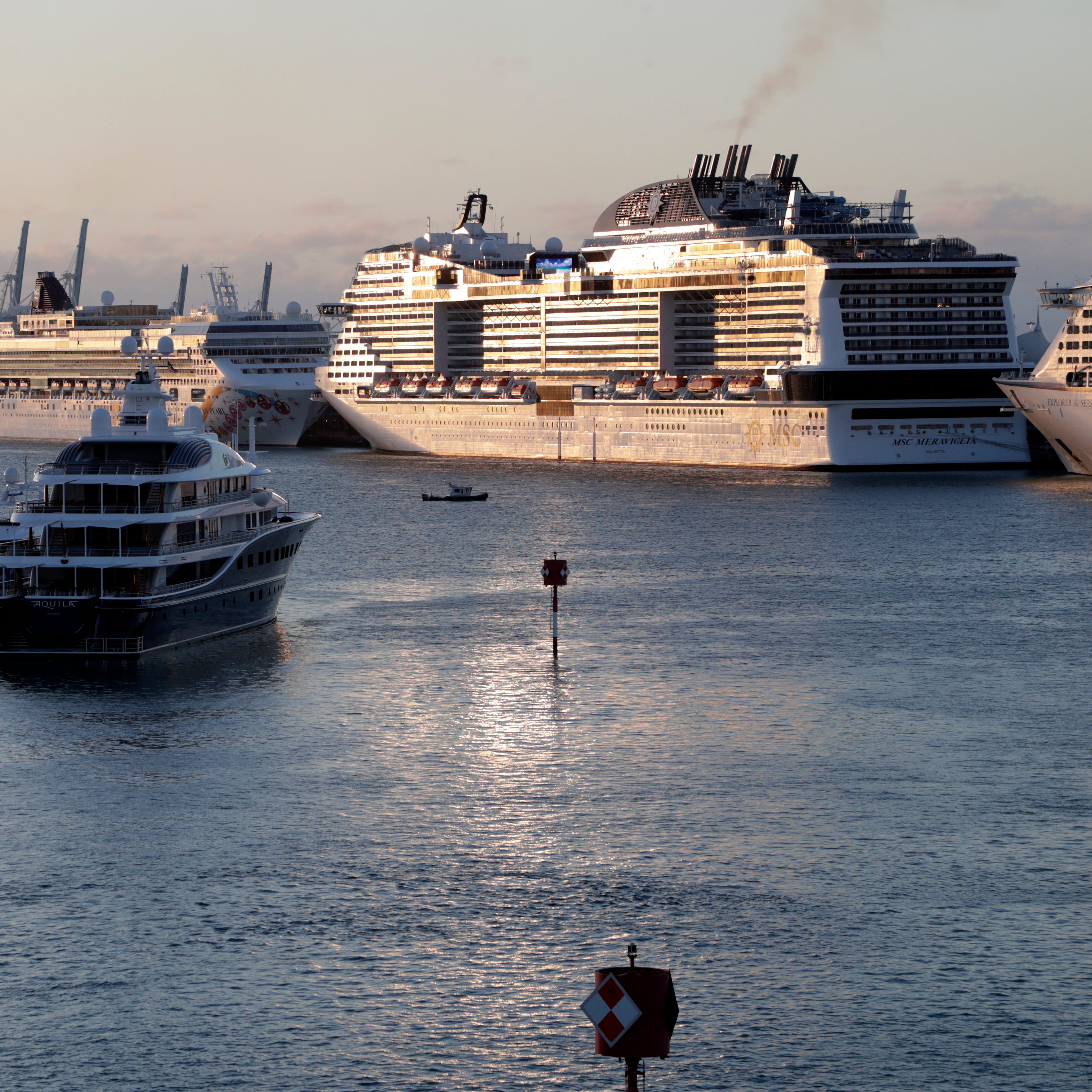 MSC Meraviglia, right, is docked with other ships at PortMiami, Sunday, March 15, 2020, in Miami Beach, Fla.