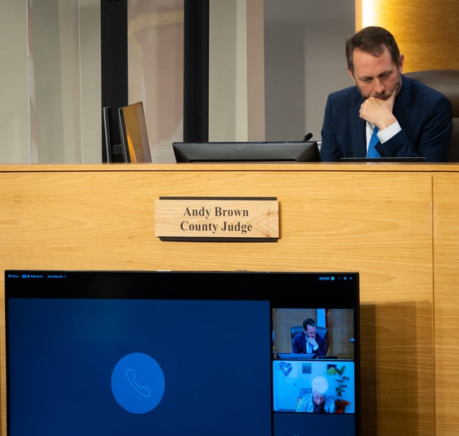 Travis County Judge Andy Brown listens for comment via telephone before a vote to begin development of a new mental and behavioral diversion center in an effort to divert people with a mental health issue away from prison at the Travis County Sheriff's Office, March 21, 2023. 