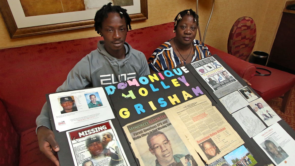 Aug 18, 2022; Concord, NC, USA;  Jaquan Holley-Grishamand his mother, Mozell Jones-Grisham hold a homemade poster inside Mozell's room at the Embassy Suites in Concord, North Carolina.    Mozell Jones-Grisham's son Domonique Holley-Grisham disappeared from his family home in Rochester, NY in February of 2009. The 16-year-old was home with his youngest brother and his mother's best friend when he received a phone call. After picking up the phone Domonique walked out of his house never to be seen again. Mandatory Credit: Michael Hensdill for USA TODAY