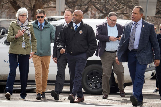 Denver Mayor Michael Hancock, center, walks across 17th Avenue to talk to parents as they wait for their children to be walked out of East High School after a school shooting Wednesday, March 22, 2023, in Denver.