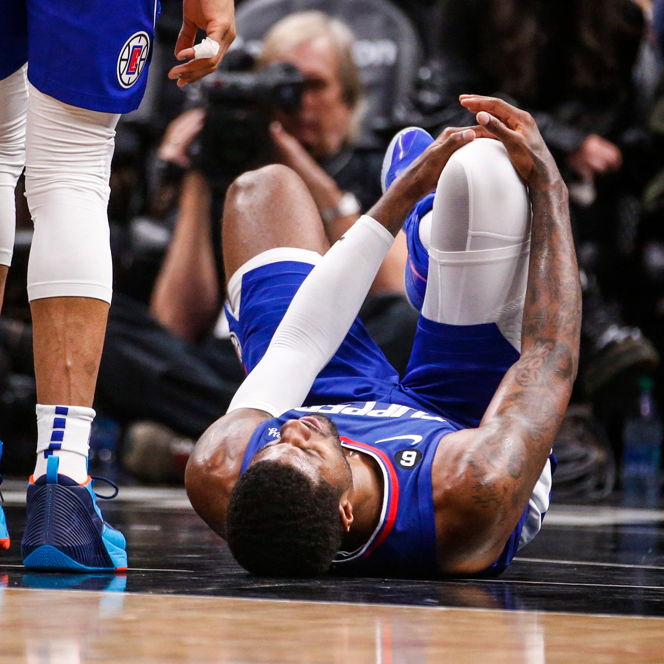 Los Angeles Clippers forward Paul George, right, lies on the court after suffering an apparent leg injury.