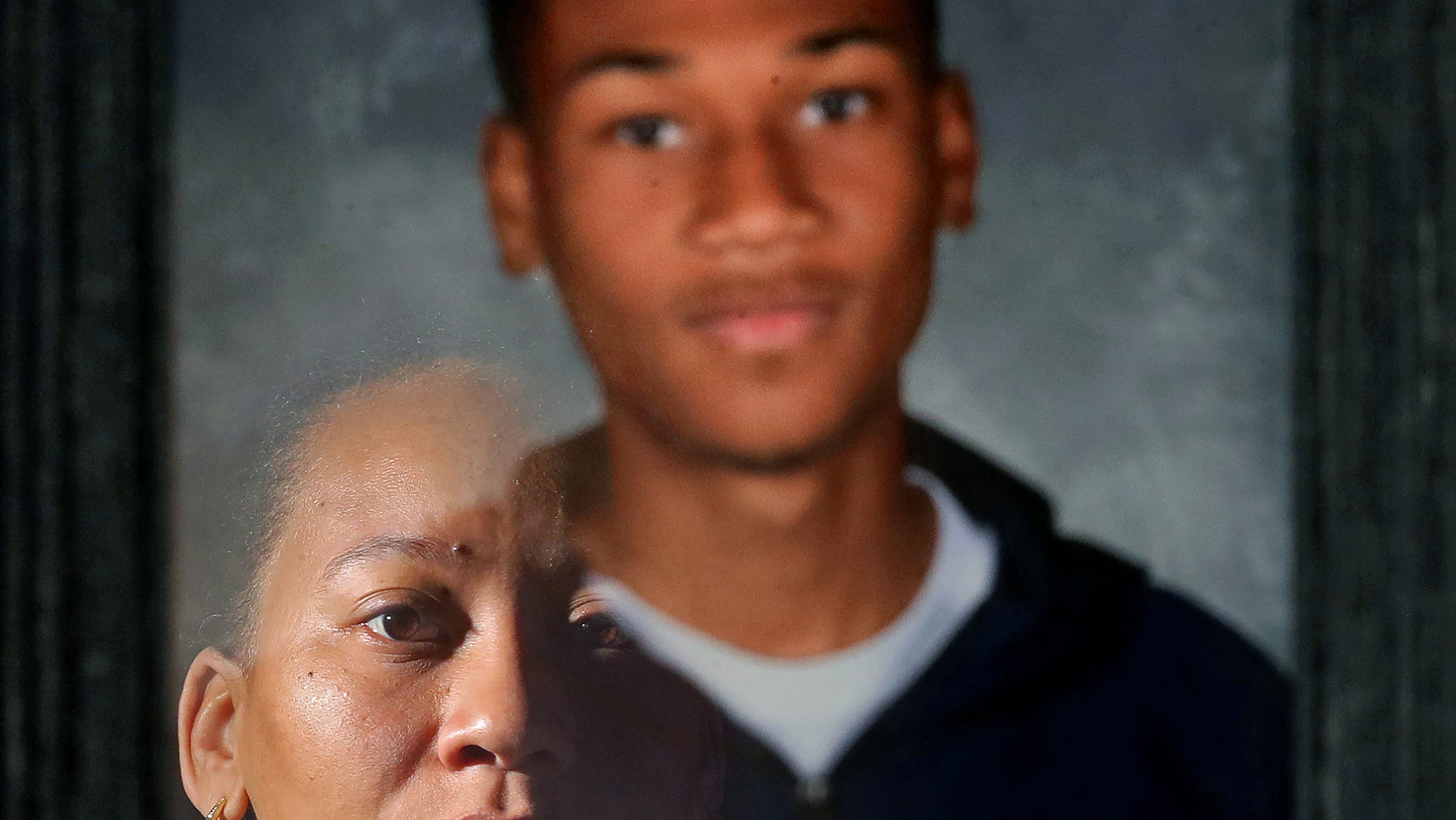 Tamia Woods is reflected in a portrait of her 17-year-old son, James, on Friday, March 24, 2023, in Streetsboro, Ohio. James took his own life in November last year after he became a victim of online sextortion.