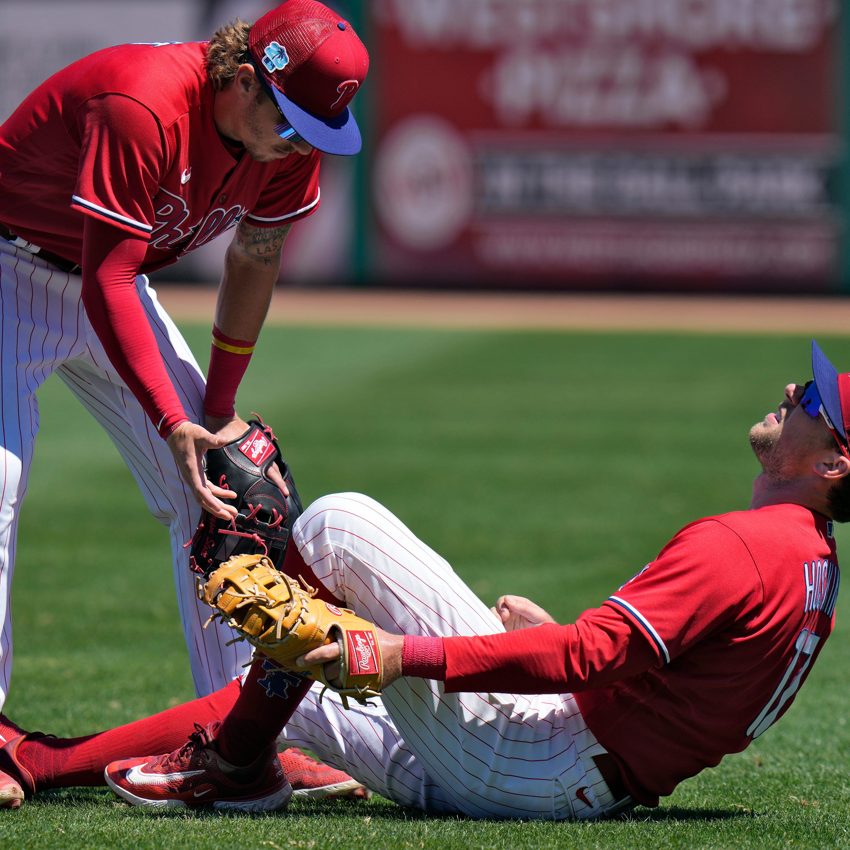 Philadelphia Phillies first baseman Rhys Hoskins (17) falls backwards after hurting his leg fielding a ground ball by Detroit Tigers' Austin Meadows during the second inning of a spring training baseball game Thursday, March 23, 2023, in Clearwater, Fla.