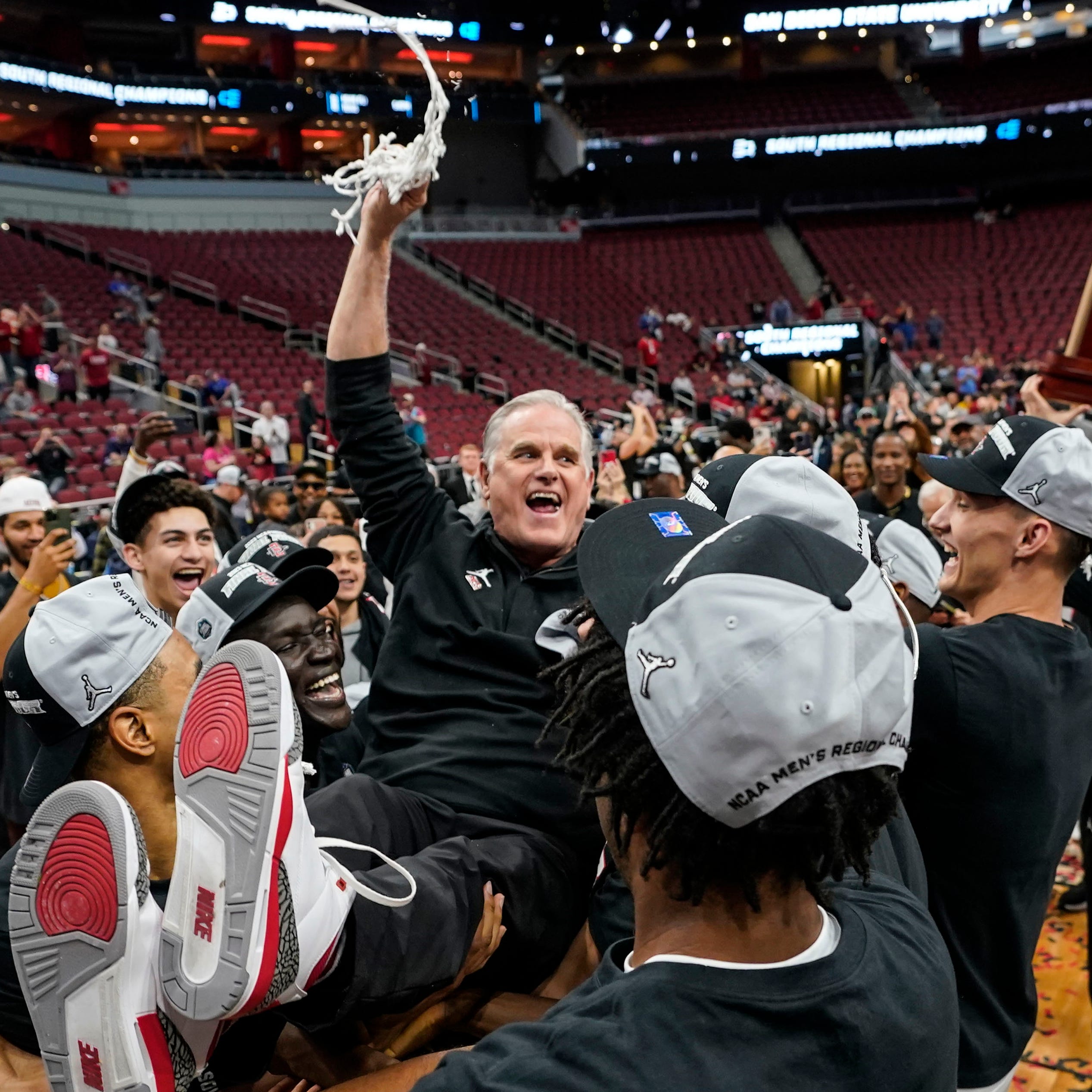 San Diego State coach Brian Dutcher holds the remains of the net after the Aztecs defeated Creighton to advance to the Final Four of the NCAA men's tournament.