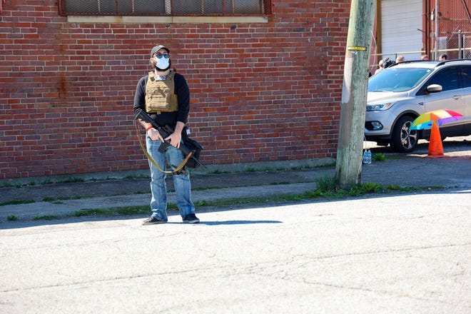 A man with a gun stands outside a recent Drag Queen Story Time event in Louisville, Ky