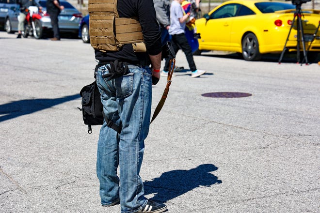 A man with a gun stands outside a recent Drag Queen Story Time event in Louisville, Ky.